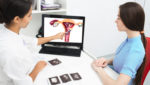 A doctor uses an image on a laptop to educate a patient on her uterine fibroids.